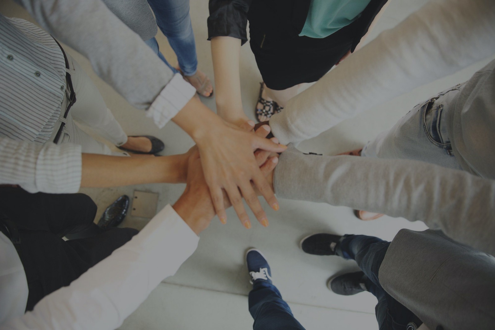 A group of people joining their hands together in the center of a circle
